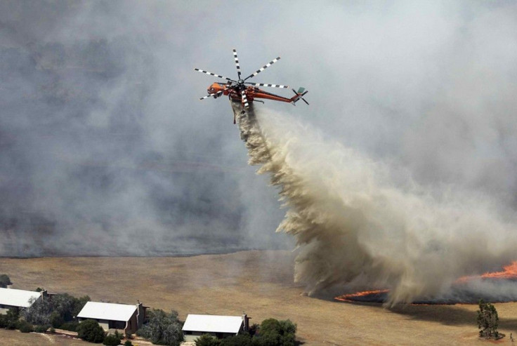 A helicopter dumps water on a bushfire burning near houses in the Grampians bushland in the southeastern Australian state of Victoria, about 300 km (186 miles) west of Melbourne, January 17, 2014