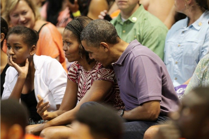 U.S President Barack Obama hugs first lady Michelle as they watch the Diamond Head basketball game between Oregon State and Akron during their Christmas vacation in Honolulu