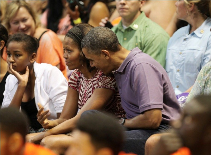 U.S President Barack Obama hugs first lady Michelle as they watch the Diamond Head basketball game between Oregon State and Akron during their Christmas vacation in Honolulu