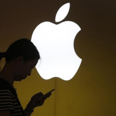 A woman looks at the screen of her mobile phone in front of an Apple logo outside its store in downtown Shanghai September 10, 2013.