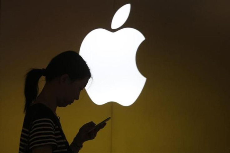 A woman looks at the screen of her mobile phone in front of an Apple logo outside its store in downtown Shanghai September 10, 2013.