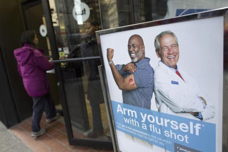 People enter a pharmacy next to a sign promoting flu shots in New York January 10, 2013. REUTERS/Andrew Kelly