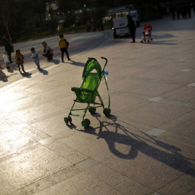 A baby stroller is seen as mothers play with their children at a public area in downtown Shanghai November 19, 2013. 