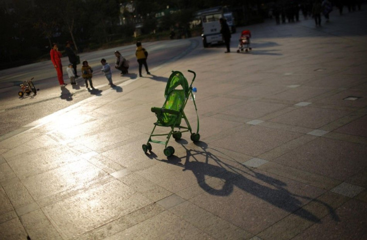 A baby stroller is seen as mothers play with their children at a public area in downtown Shanghai November 19, 2013. 