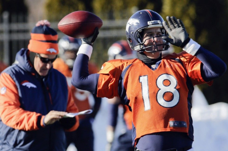 Denver Broncos&#039; Adam Gase checks clipboard as teammate Peyton Manning throws a pass during their practice for Super Bowl in Florham Park