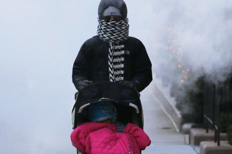 A woman pushes a baby stroller through a cloud of steam from a construction site in Boston, Massachusetts January 7, 2014. A deadly blast of arctic air that shattered decades-old records as it gripped the middle United States moved eastward on Tuesday, ca