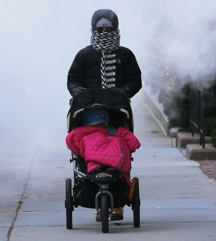 A woman pushes a baby stroller through a cloud of steam from a construction site in Boston, Massachusetts January 7, 2014. A deadly blast of arctic air that shattered decades-old records as it gripped the middle United States moved eastward on Tuesday, ca
