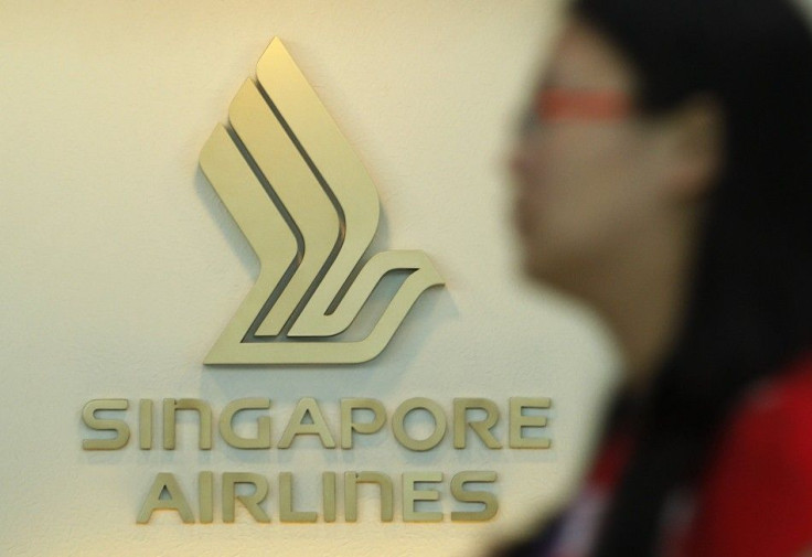A woman walks past a Singapore Airlines (SIA) logo at a ticketing booth at Changi airport in Singapore May 14, 2013. Singapore Airlines Ltd, caught between the rapid emergence of Gulf carriers and low cost Asian rivals, is attempting a big strategy overha