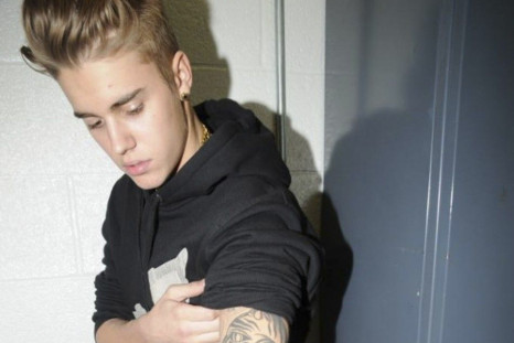 Canadian pop singer Justin Bieber shows his tattooed left arm, while in police custody in Miami Beach, Florida January 23, 2014 in this Miami Beach Police Department handout released to Reuters on March 4, 2014. Bieber was charged with driving under the i