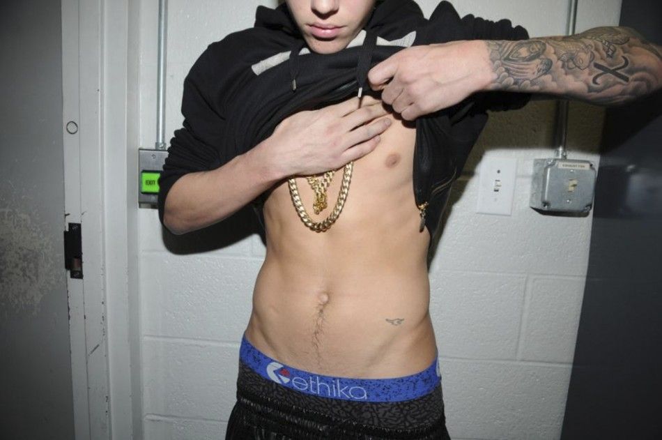 Canadian pop singer Justin Bieber lifts his T-shirt, while in police custody in Miami Beach, Florida