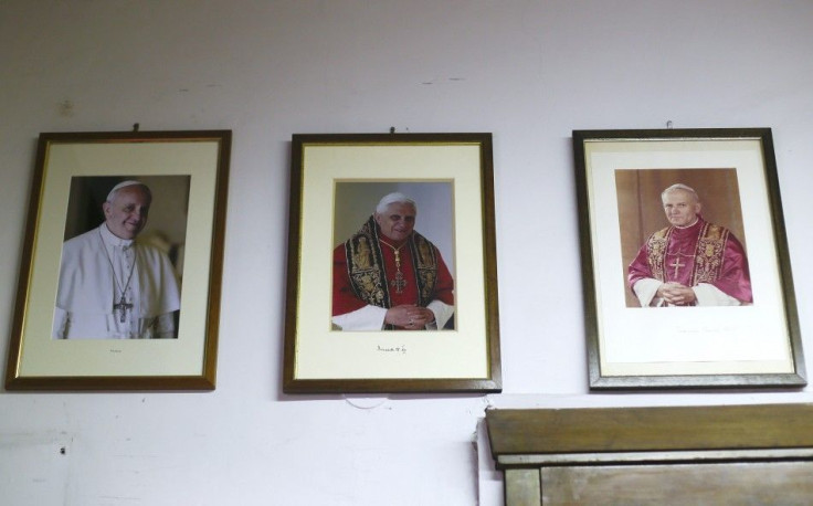 Framed pictures of Pope Francis (L-R), Pope Benedict XVI and Pope John Paul II hang on the wall inside the Gammarelli tailor shop in Rome February 11, 2014. As the Vatican prepares to welcome 19 prelates to the high rank of cardinal, Pope Francis' call fo