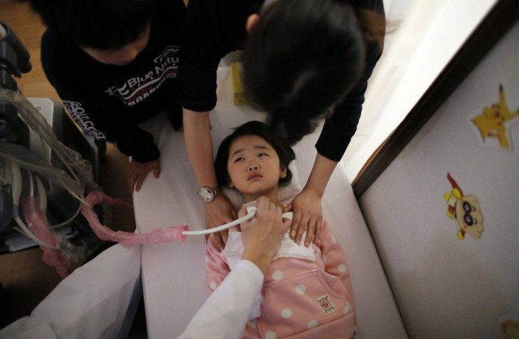 A doctor conducts a thyroid examination on five-year-old girl as her older brother and a nurse take care of her at a clinic in temporary housing complex in Nihonmatsu, west of the tsunami-crippled Fukushima Daiichi nuclear power plant, Fukushima prefectur