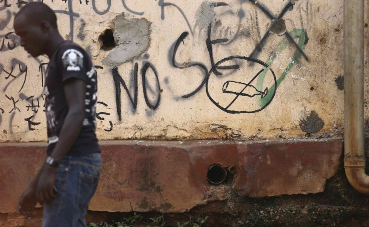 A man walks past graffiti about sex in downtown Kampala