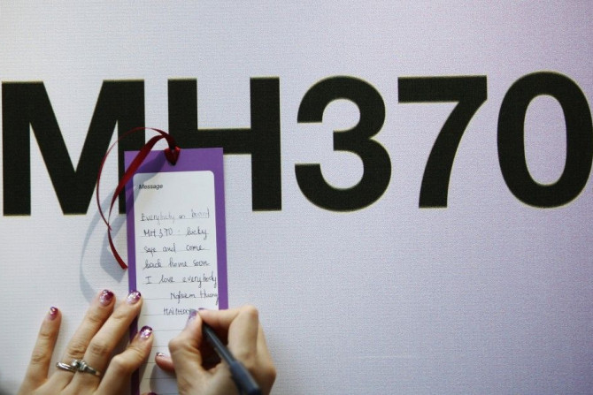 A tourist writes a message expressing hope for family members and those onboard the missing Malaysia Airlines flight MH370, in Kuala Lumpur