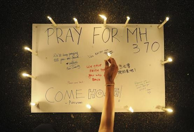 A woman places a lighted candle on a poster with messages expressing hope for passengers of the missing Malaysia Airlines plane MH370 during a candlelight vigil in Petaling Jaya, near Kuala Lumpur on 16 March, 2014.