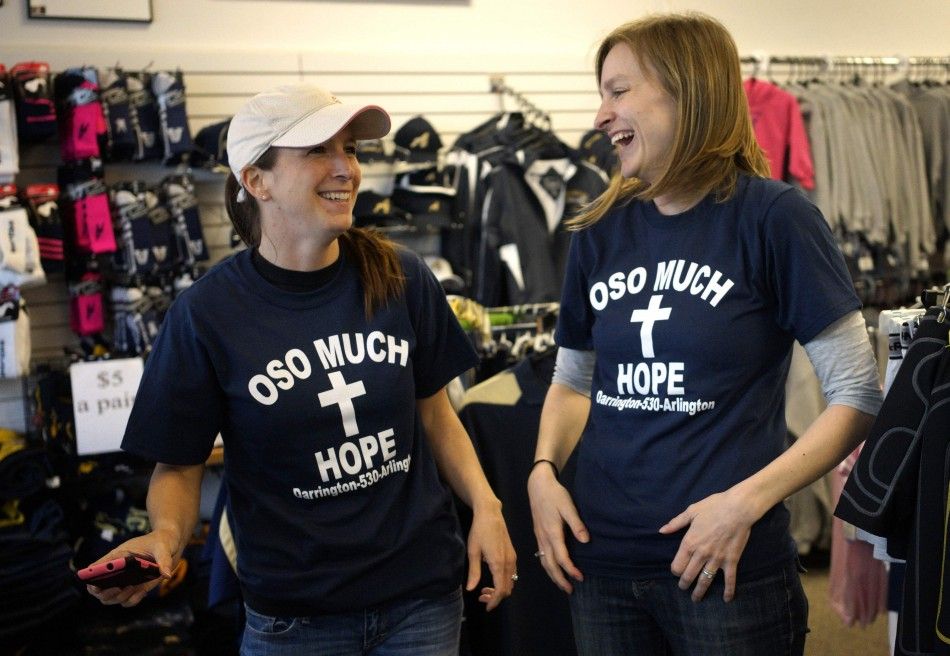 Women try on the new Oso mudslide support t-shirts in the Action Sports shop in downtown Arlington