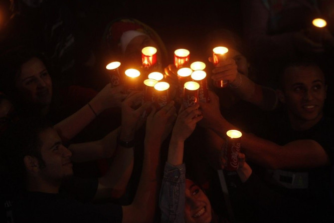People hold candles during Earth Hour after the lights were turned off in central Amman March 29, 2014.