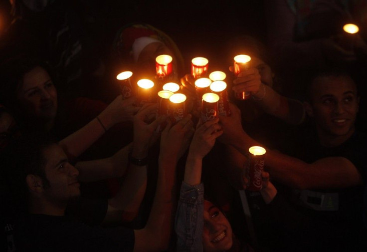 People hold candles during Earth Hour after the lights were turned off in central Amman March 29, 2014.