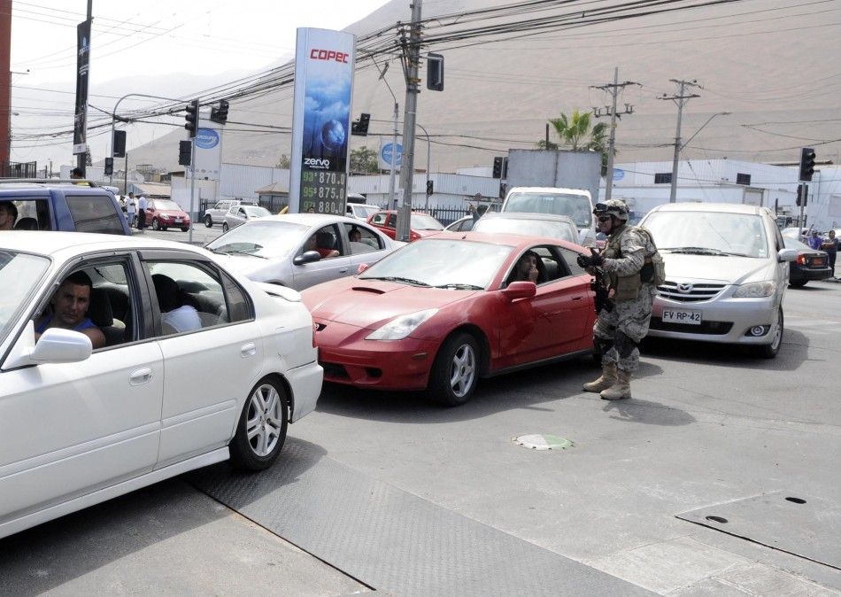 A soldier maintains order as dozens of cars lined up to buy fuel after an earthquake and tsunami hit the northern port of Iquique, April 2, 2014. The earthquake, with a magnitude of 8.2, struck off the coast of northern Chile near the copper exporting por