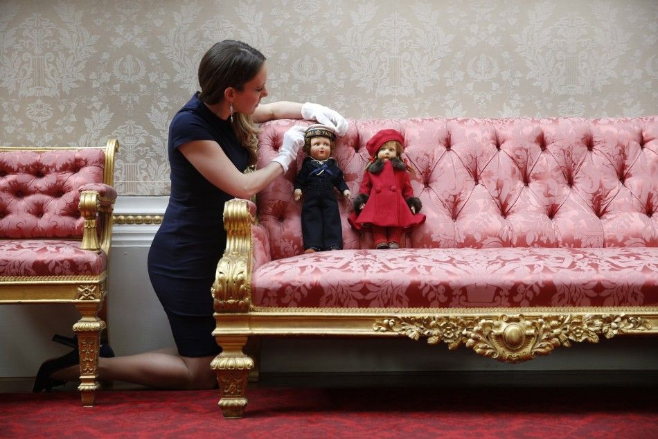 Exhibition curator Anna Reynolds poses with dolls belonging to Britains Queen Elizabeth, at Buckingham Palace in London
