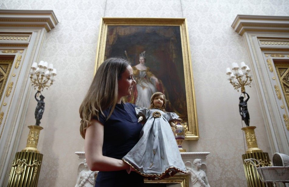 Exhibition curator Anna Reynolds poses with a Parisian doll belonging to Britains Queen Elizabeth, at Buckingham Palace in London