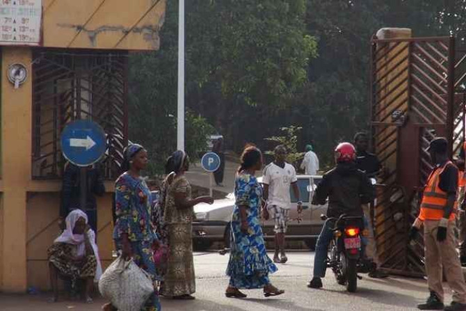 People walk in front of the entrance of the Donka Hospital, where victims of the ebola disease are being treated,