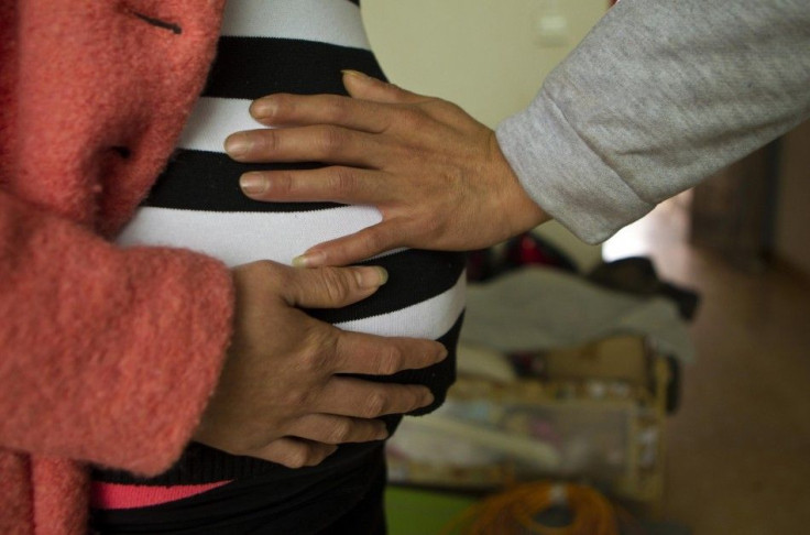 Lu Libing touches the belly of his pregnant wife, Mu, as they pose for pictures during an interview with Reuters at their home in Ganzhou