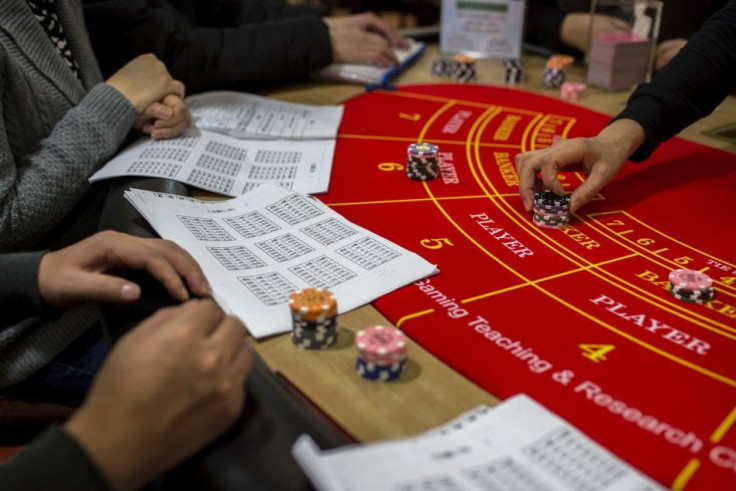 A student (R) practices distributing chips during a gaming lesson at a mock casino run by the Macao Polytechnic Institute (MPI) Gaming Teaching and Research Centre in Macau March 6, 2014. Galaxy Entertainment Group Ltd and Melco Crown Entertainment Ltd lo