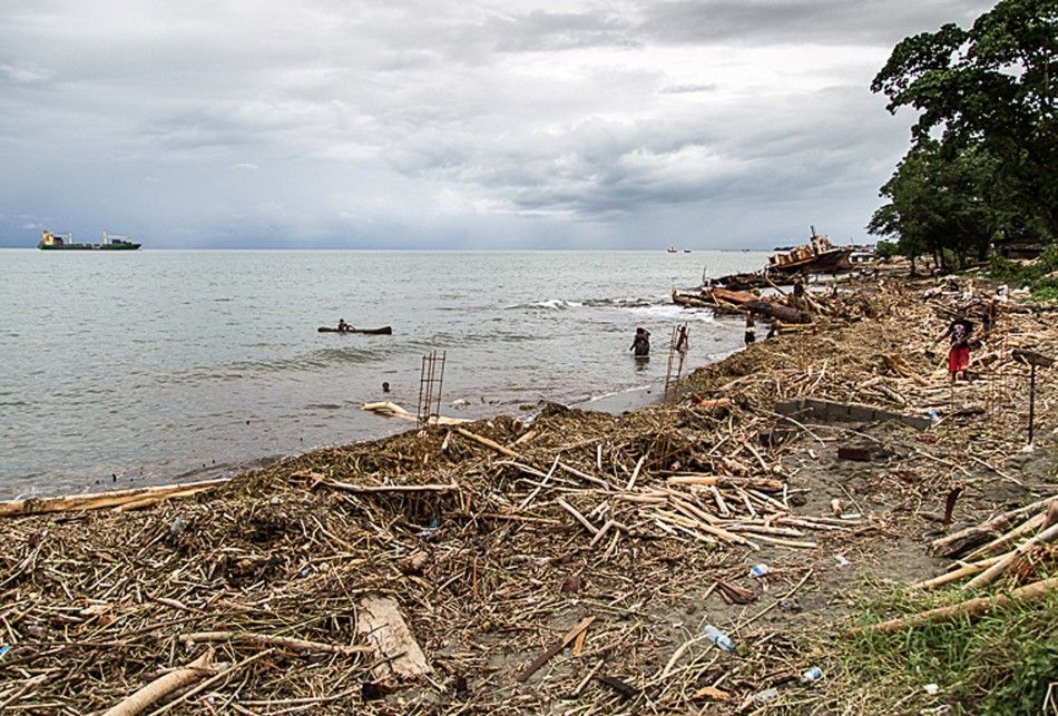 Locals walk amongst debris that was washed ashore as a result of severe flooding near the capital Honiara in the Solomon Islands in this picture released by World Vision April 6, 2014. Local media reported that the United Nations Office for the Coordinati
