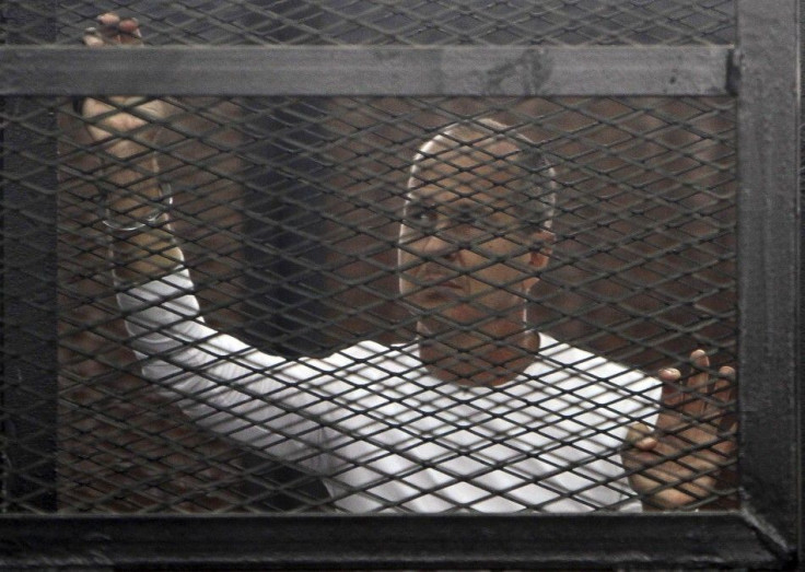 Al Jazeera journalist Peter Greste of Australia stands in a metal cage during his trial in a court in Cairo