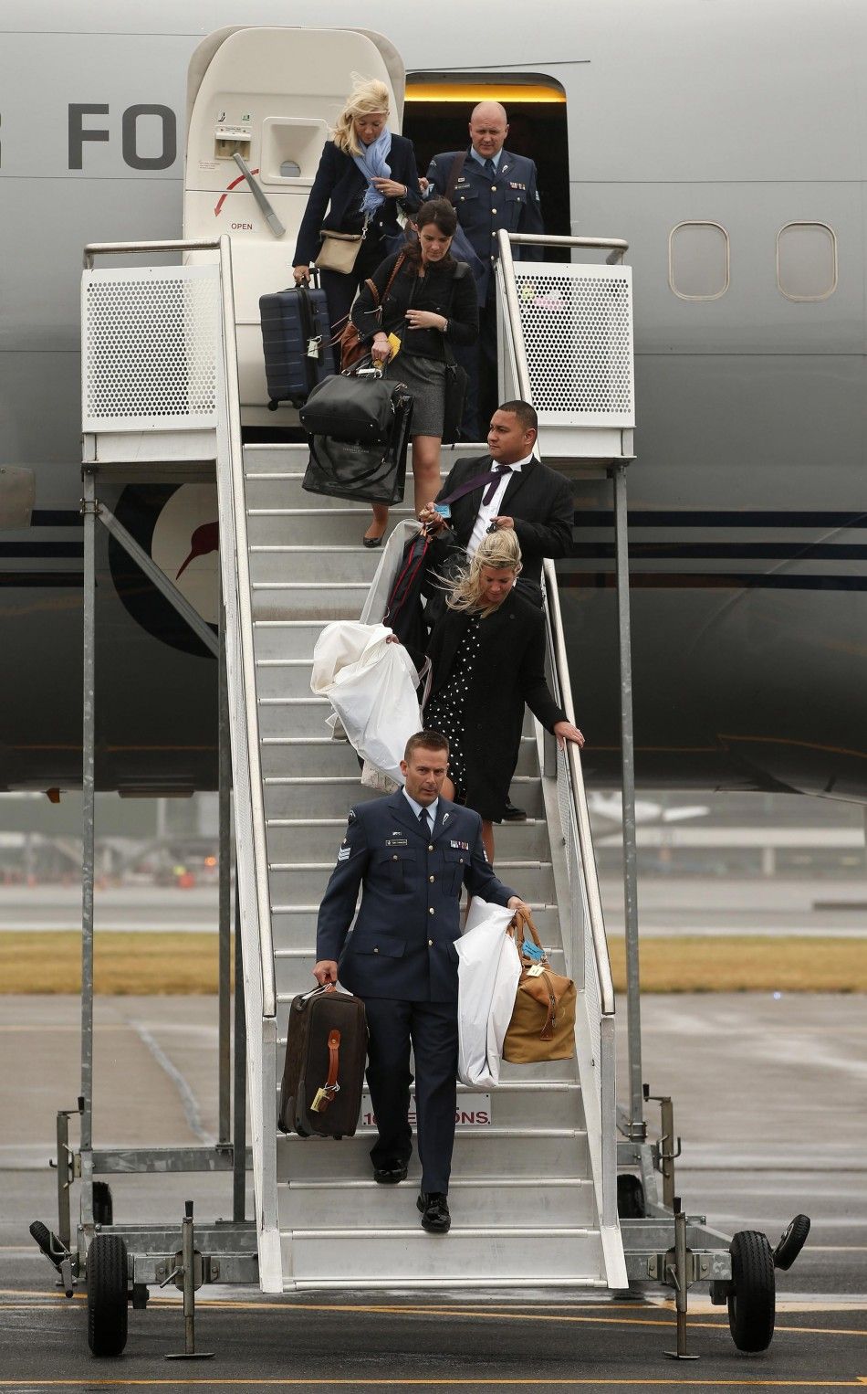 Members of the Royal New Zealand Airforce and the royal household carry luggage from the royal plane after arriving in Wellington April 7, 2014. Britains Prince William and his wife Kate are undertaking a19-day official visit to New Zealand and Australia