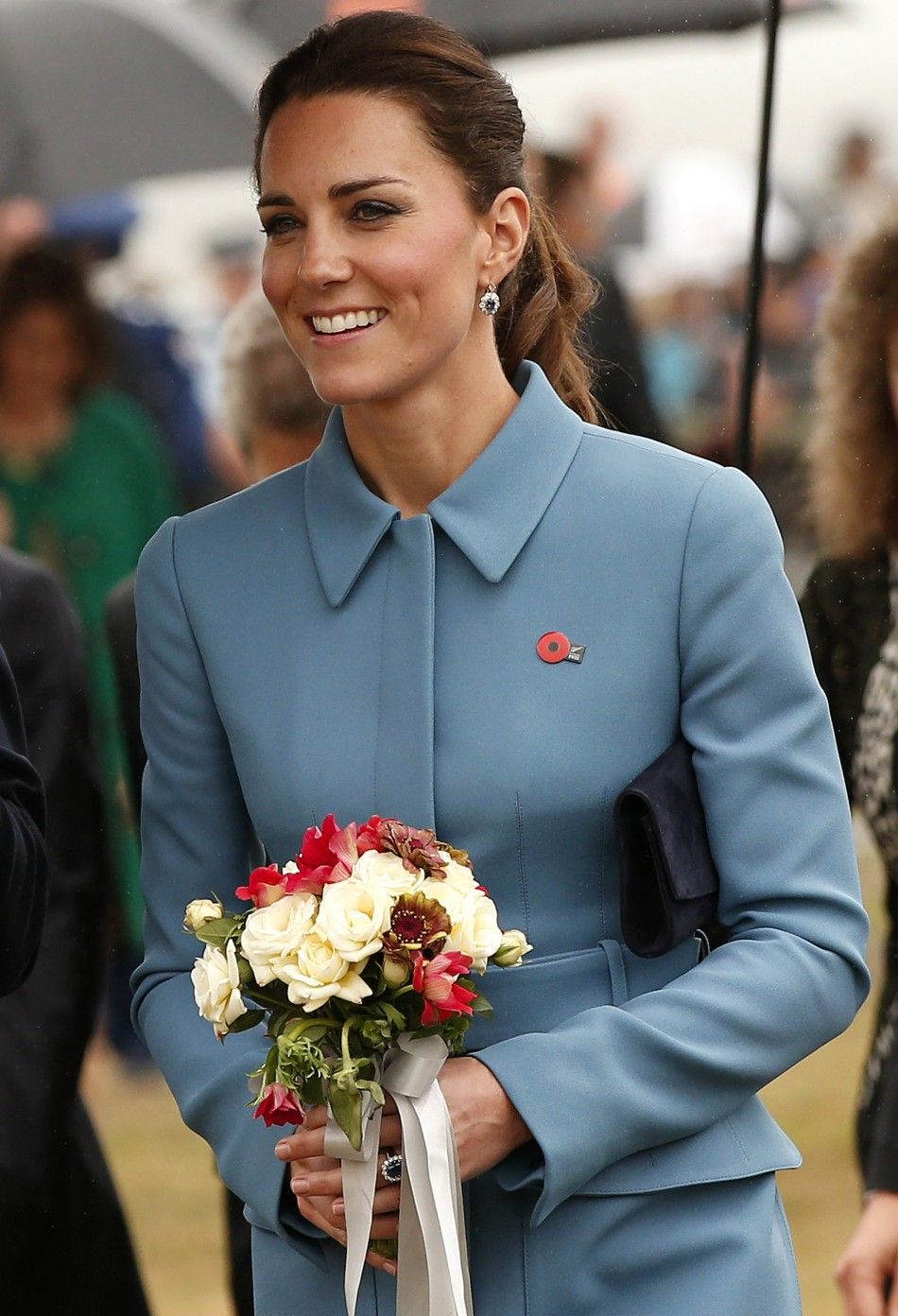 Britains Catherine, the Duchess of Cambridge, smiles as she carries flowers at the Omaka Aviation Heritage Center near Blenheim