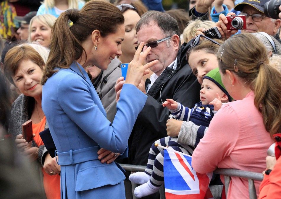 Catherine, the Duchess of Cambridge, reacts as she greets a baby after laying a wreath with her husband, Britains Prince William, at the war memorial in Seymour Square