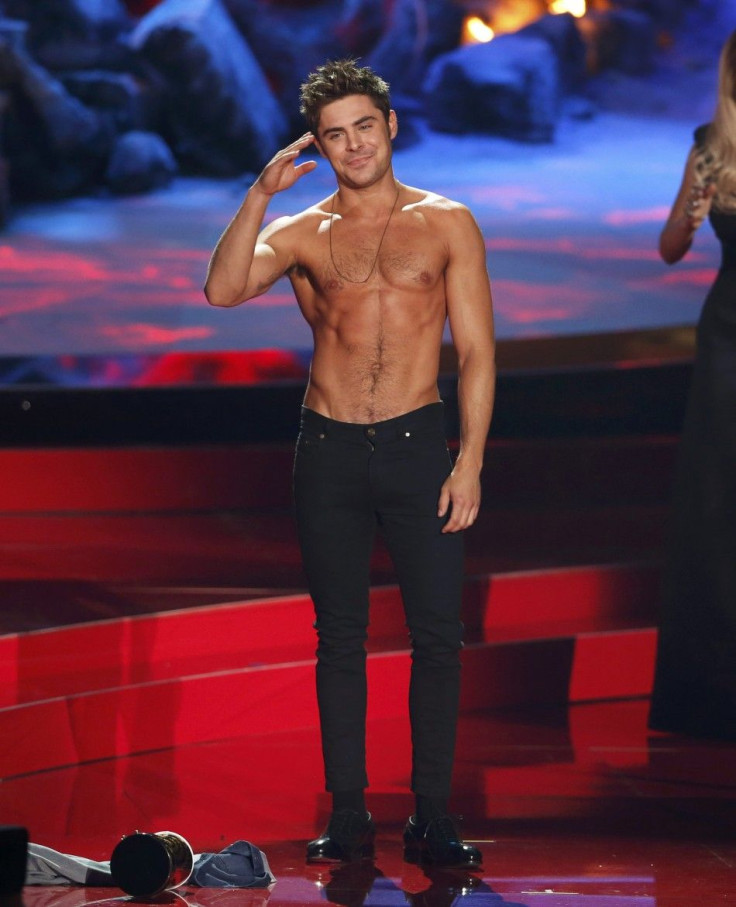 Zac Efron Poses After He Threw Off His Shirt as He Accepts the Award for Best Shirtless Performance for 'That Awkward Moment' as Presenters Rita Ora and Jessica Alba Look on at the 2014 MTV Movie Awards in Los Angeles