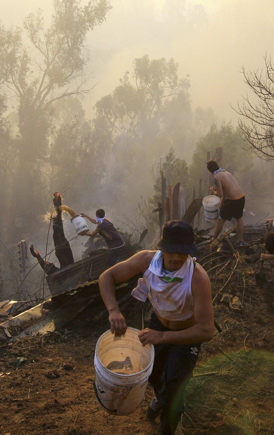 Residents work to put down a fire at the location where a forest fire burned several neighbourhoods in the hills in Valparaiso city, northwest of Santiago, April 13, 2014. At least 11 people were killed and 500 houses destroyed over the weekend by the fir