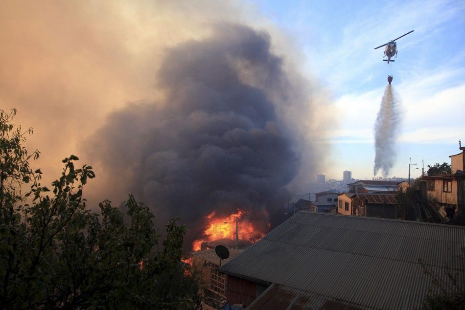 A helicopter assists in fighting a fire at the location where a forest fire burned several neighbourhoods in the hills in Valparaiso city, northwest of Santiago, April 13, 2014. At least 11 people were killed and 500 houses destroyed over the weekend by t