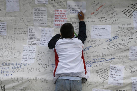 A man writes a message wishing for the safe return of missing passengers of the South Korean ferry Sewol, which capsized in the sea off Jindo last week, at a port in Jindo April 21, 2014. South Korean President Park Geun-hye said on Monday the actions of 