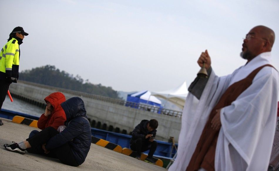 A Buddhist monk prays near family members of a missing passenger onboard South Korean ferry Sewol, which capsized on Wednesday, as they look at the sea at a port in Jindo April 22, 2014. South Korean President Park Geun-hye said on Monday the actions of s