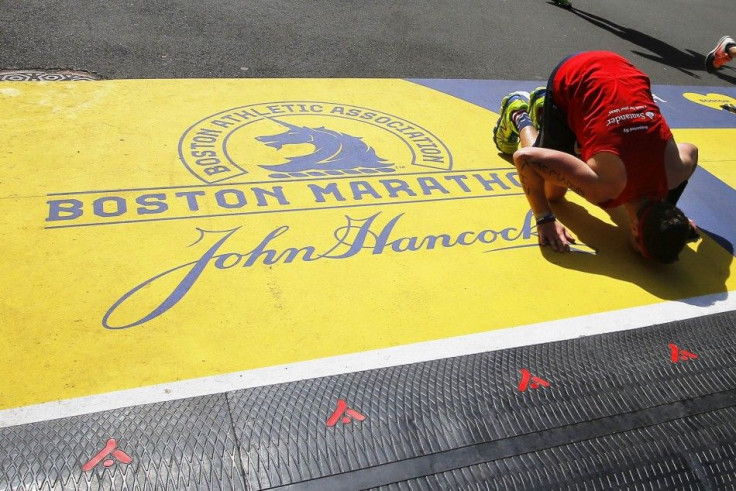 A runner kisses the finish line after completing the 118th Boston Marathon in Boston
