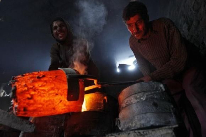 Workers pour melted copper in a mould to make utensils and accessories inside a workshop in Srinagar.