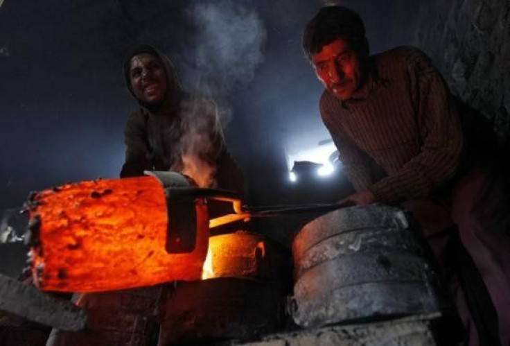 Workers pour melted copper in a mould to make utensils and accessories inside a workshop in Srinagar.