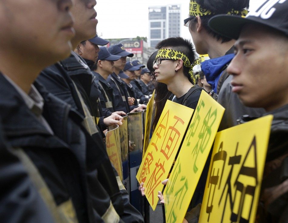 Anti-nuclear activists hold signs in front of a row of police officers standing guard during a protest at Taiwans ruling Nationalist Party KMT headquaters in Taipei April 23, 2014. Activists demand the government to stop the controversial construction 