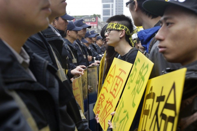 Anti-nuclear activists hold signs in front of a row of police officers standing guard during a protest at Taiwan's ruling Nationalist Party (KMT) headquaters in Taipei April 23, 2014. Activists demand the government to stop the controversial construction 