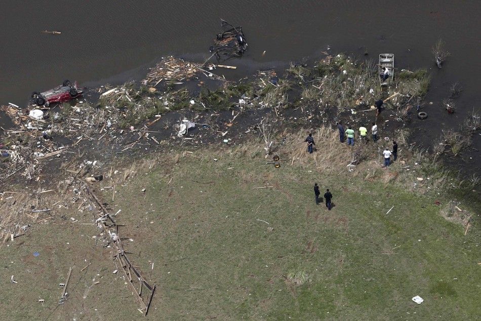 Vehicles and debris litter a lake as rescue workers and volunteers search the area one day after the area was destroyed by a tornado near Vilonia, Arkansas April 28, 2014. A ferocious storm system caused a twister in Mississippi and threatened tens of mil
