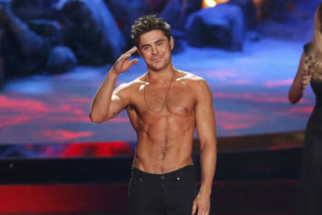 Zac Efron poses after he threw off his shirt as he accepts the award for best shirtless performance for &quot;That Awkward Moment&quot; as presenters Rita Ora and Jessica Alba (2nd R) look on at the 2014 MTV Movie Awards in Los Angeles, California  April 