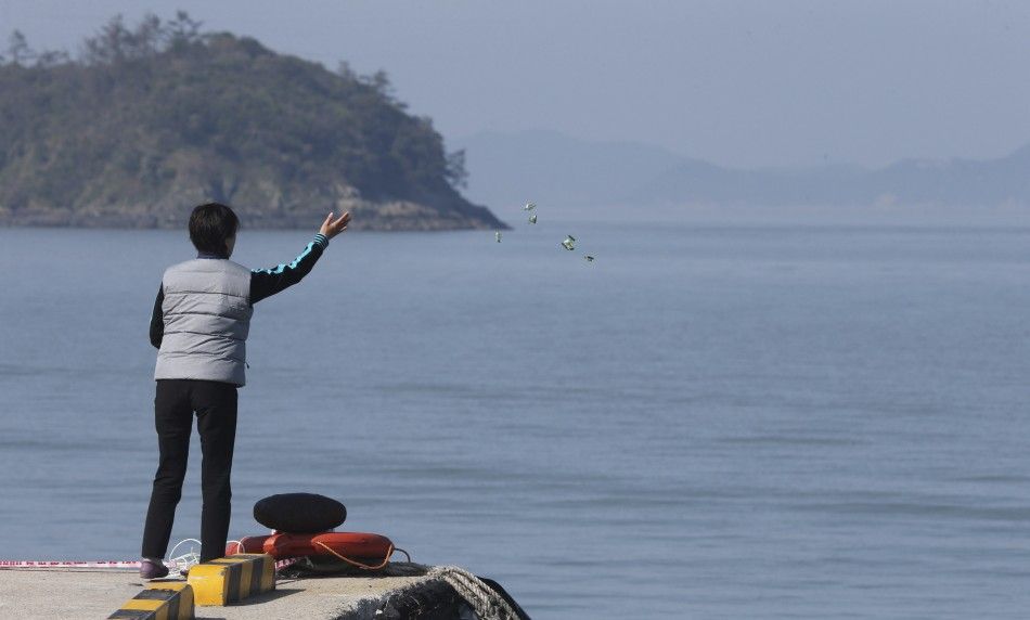 A family member of missing passengers onboard the sunken passenger ship Sewol scatters candies over the sea as she waits for news from a search and rescue operation team at a port in Jindo May 1, 2014. The Sewol ferry sank on a routine trip south from the