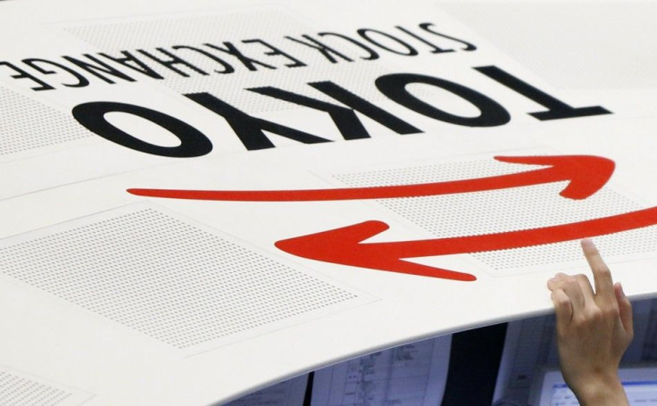 An employee of the Tokyo Stock Exchange (TSE) places his hand next to the TSE logo at the bourse in Tokyo