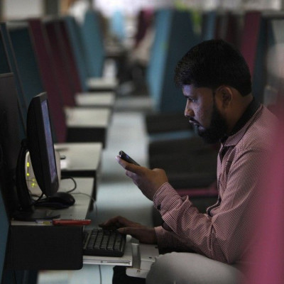 A broker monitors the market from his booth during a trading session at Karachi Stock Exchange
