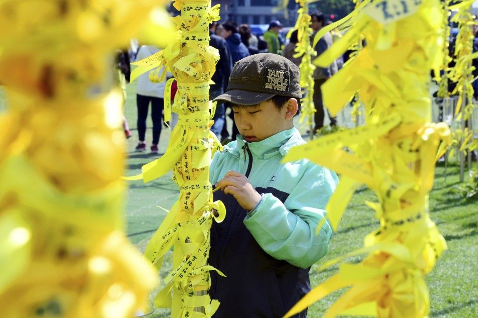 A boy ties a yellow ribbon dedicated to missing and dead passengers of the sunken passenger ship Sewol on a pillar at Yellow Ribbons Garden set up at Seoul City Hall Plaza May 5, 2014. A culture of cosy personal ties that can blur the lines between busin