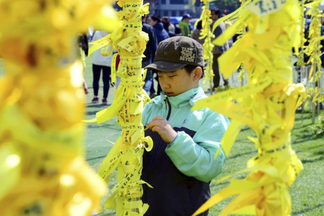 A boy ties a yellow ribbon dedicated to missing and dead passengers of the sunken passenger ship Sewol on a pillar at Yellow Ribbon's Garden set up at Seoul City Hall Plaza May 5, 2014. A culture of cosy personal ties that can blur the lines between busin
